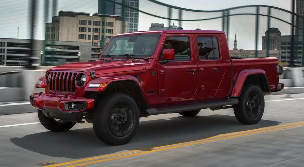 A red 2021 Jeep Gladiator driving over a bridge to a used Jeep dealer near Poughkeepsie.