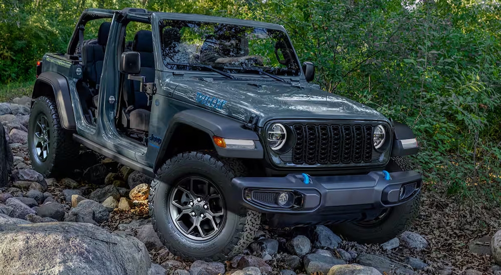 A silver 2024 Jeep Wrangler Willys 4xe off-roading down a rocky trail.