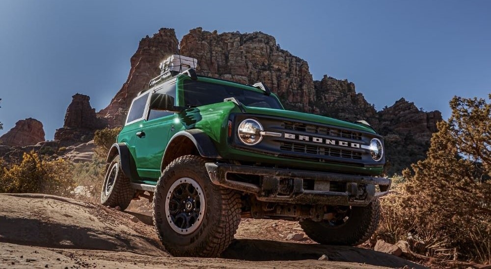 A green 2023 Ford Bronco Outer Banks driving down a dirt hill.