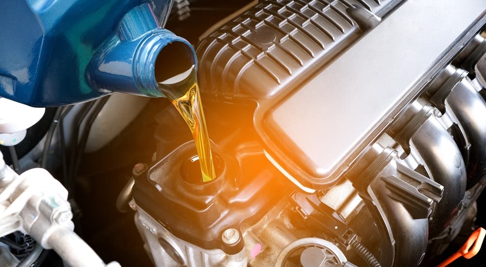 A blue oil can being poured into an engine block during an oil change near me.