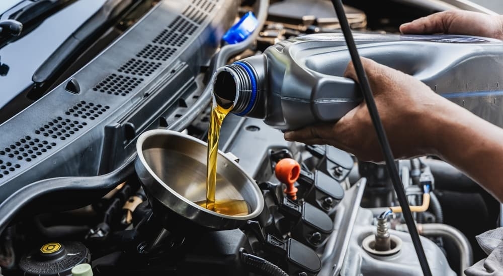 A grey oil can being poured into a funnel.