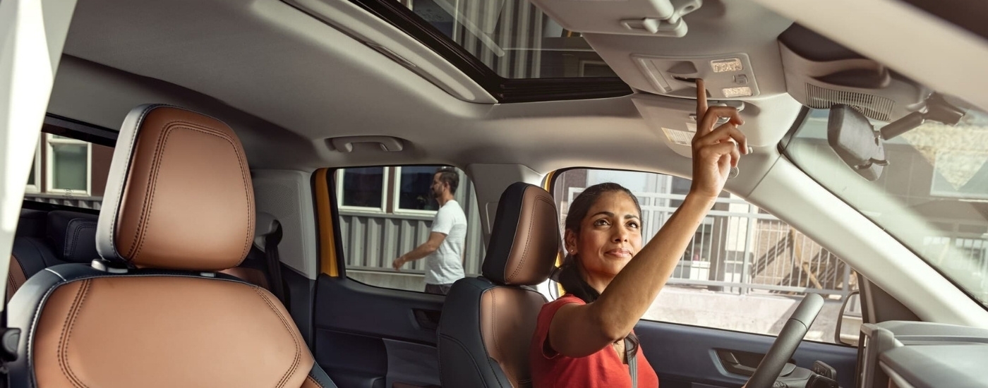 A person is shown opening the moonroof in a 2022 Ford Maverick for sale.