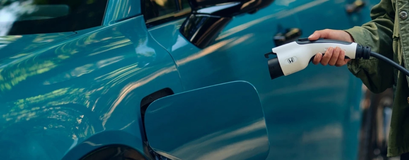 A person is shown charging a teal 2024 Honda Prologue Elite.