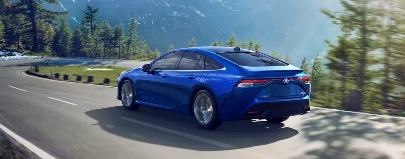 A blue 2023 Toyota Mirai Limited is shown rounding a corner on a mountain road.