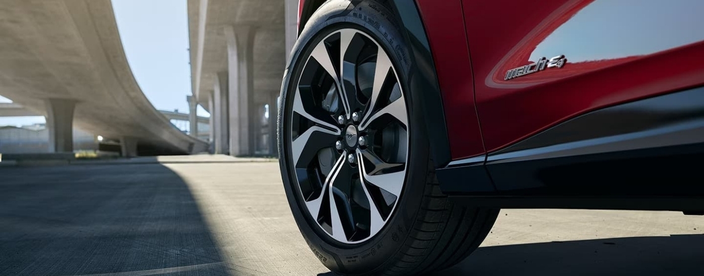 A close up shows a wheel on a red 2022 Ford Mustang Mach-E.