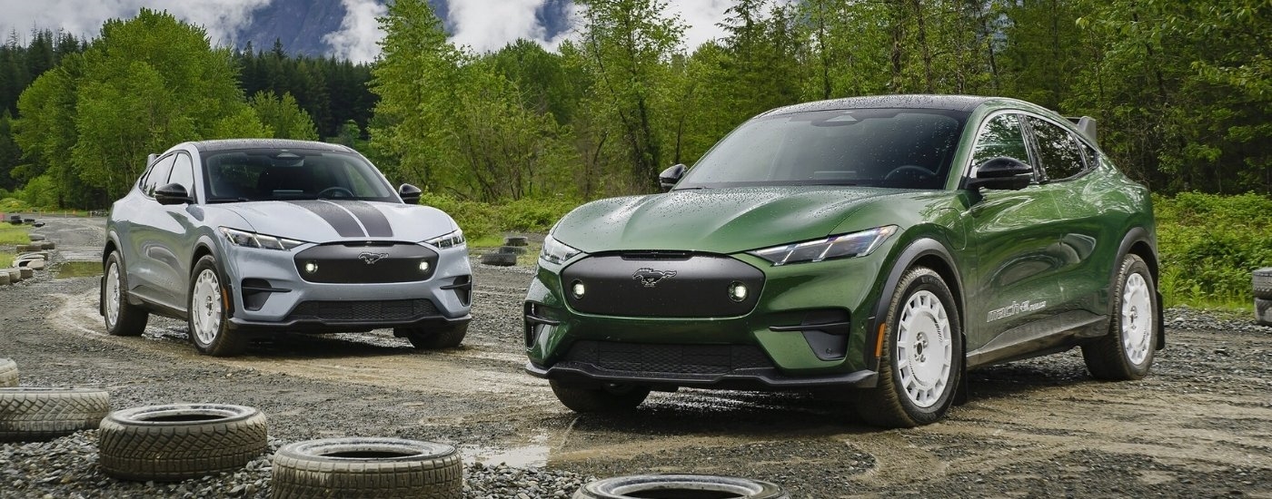 A grey and a green 2024 Ford Mustang Mach-E Rally are shown off-road.