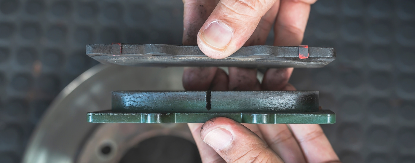 Close-up of two brake pads, one new and one used.