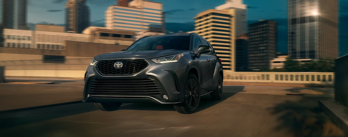 A grey 2024 Toyota Highlander XSE driving through the city.