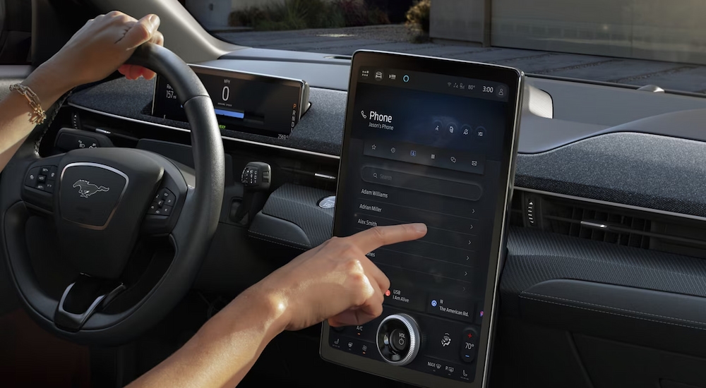 A driver using the infotainment screen in a 2024 Ford Mustang Mach-E for sale near Keene.