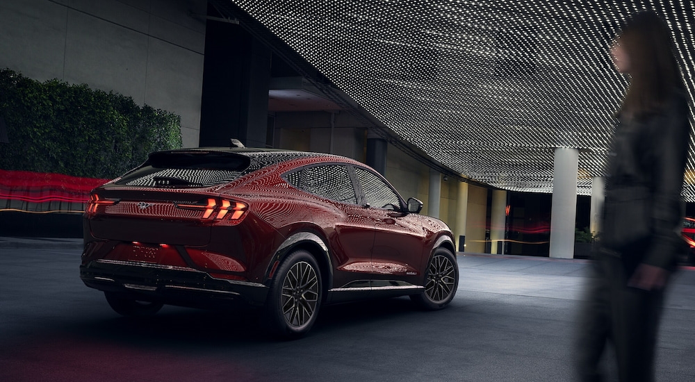 Rear view of a red 2024 Ford Mustang Mach-E Premium parked under lights at night.