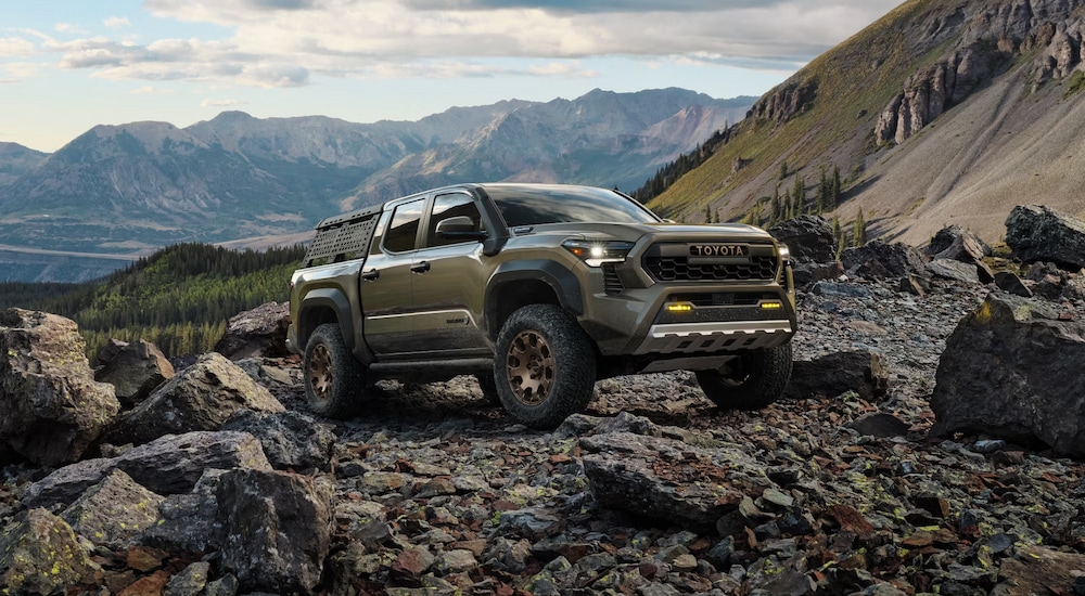 A green 2024 Toyota Tacoma iForceMAX Trailhunter parked on a rocky mountain.