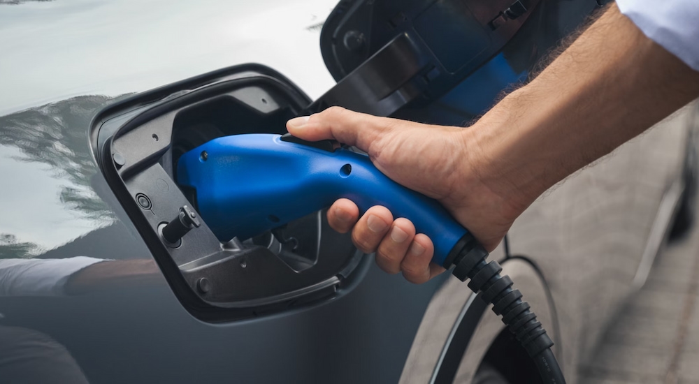 Close-up of a charger being plugged into a silver 2025 Toyota Prius XSE PHEV at a Toyota dealer near Bennington.