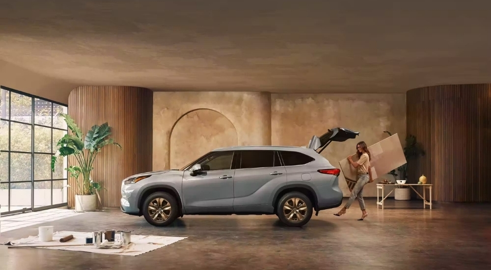 A grey 2023 Toyota Highlander Hybrid Bronze Edition is shown from the side in a modern home.