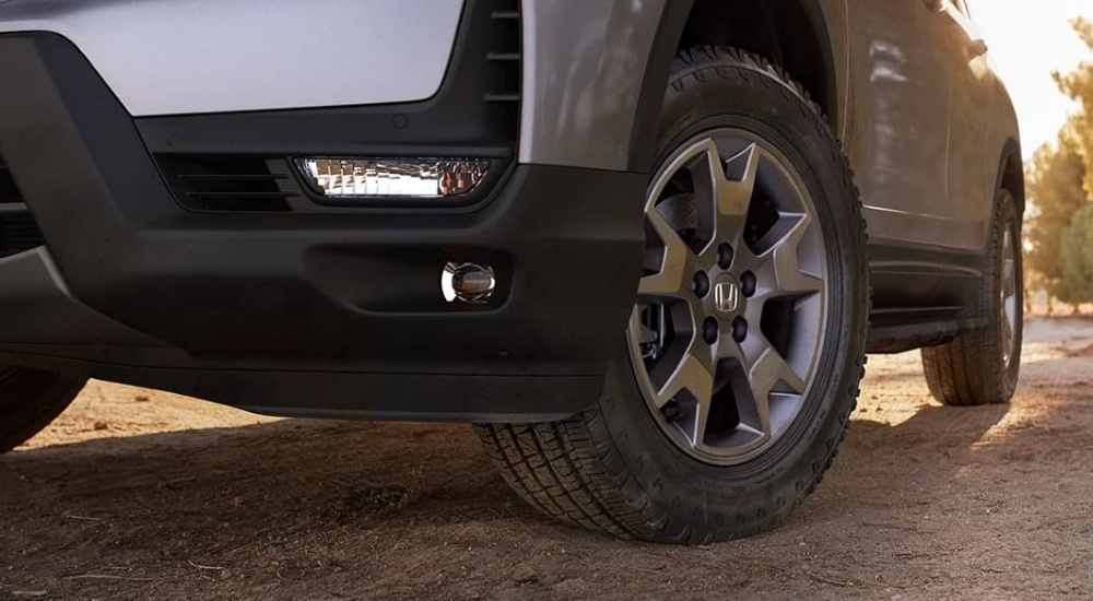 A close-up shows a wheel on a silver 2025 Honda Passport TrailSport.