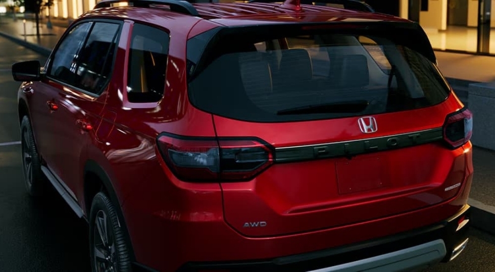 A close-up shows the rear of a red 2025 Honda Pilot Touring.