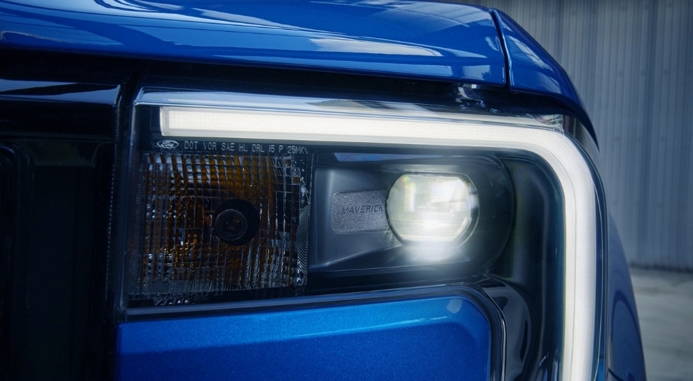 A close-up shows the driver side headlight on a blue 2025 Ford Maverick.