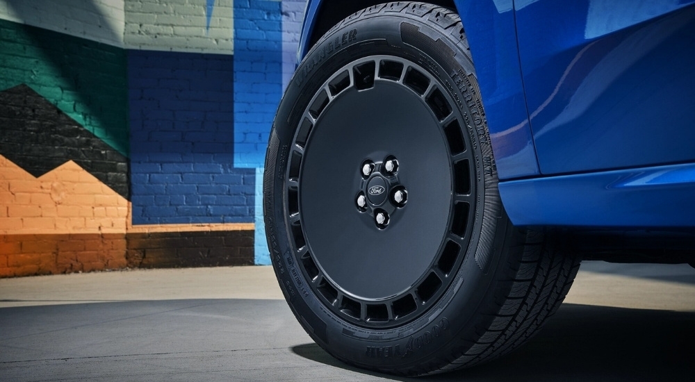 A close-up shows a black wheel on a blue 2025 Ford Maverick LOBO.