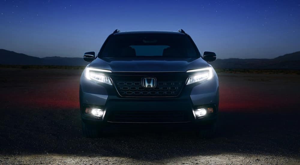 Front angle view of a grey 2021 Honda Passport parked off-road at night.