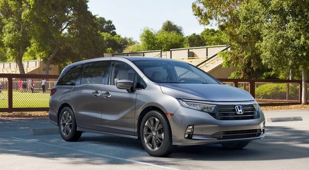 A grey 2022 Honda Odyssey Elite parked by a fence.