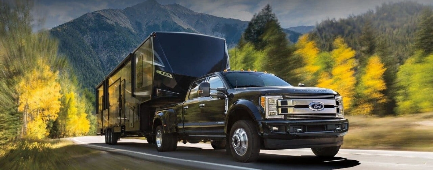 A popular used Ford for sale in Westminister, a black 2018 Ford F-450 Super Duty, is shown towing a trailer.