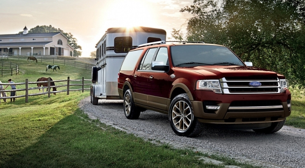 A red 2017 Ford Expedition King Ranch is shown towing a horse trailer.