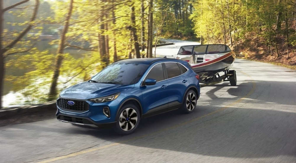 A popular used Ford for sale in Westminster, a blue 2023 Ford Escape, is shown towing a boat.