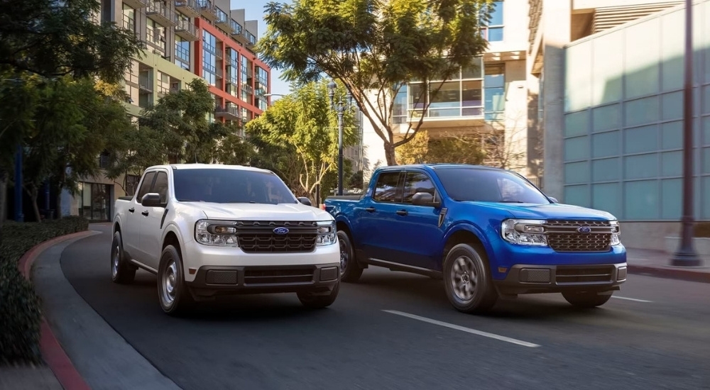 A white 2022 Ford Maverick XL and blue Maverick XLT are shown driving on a city street.