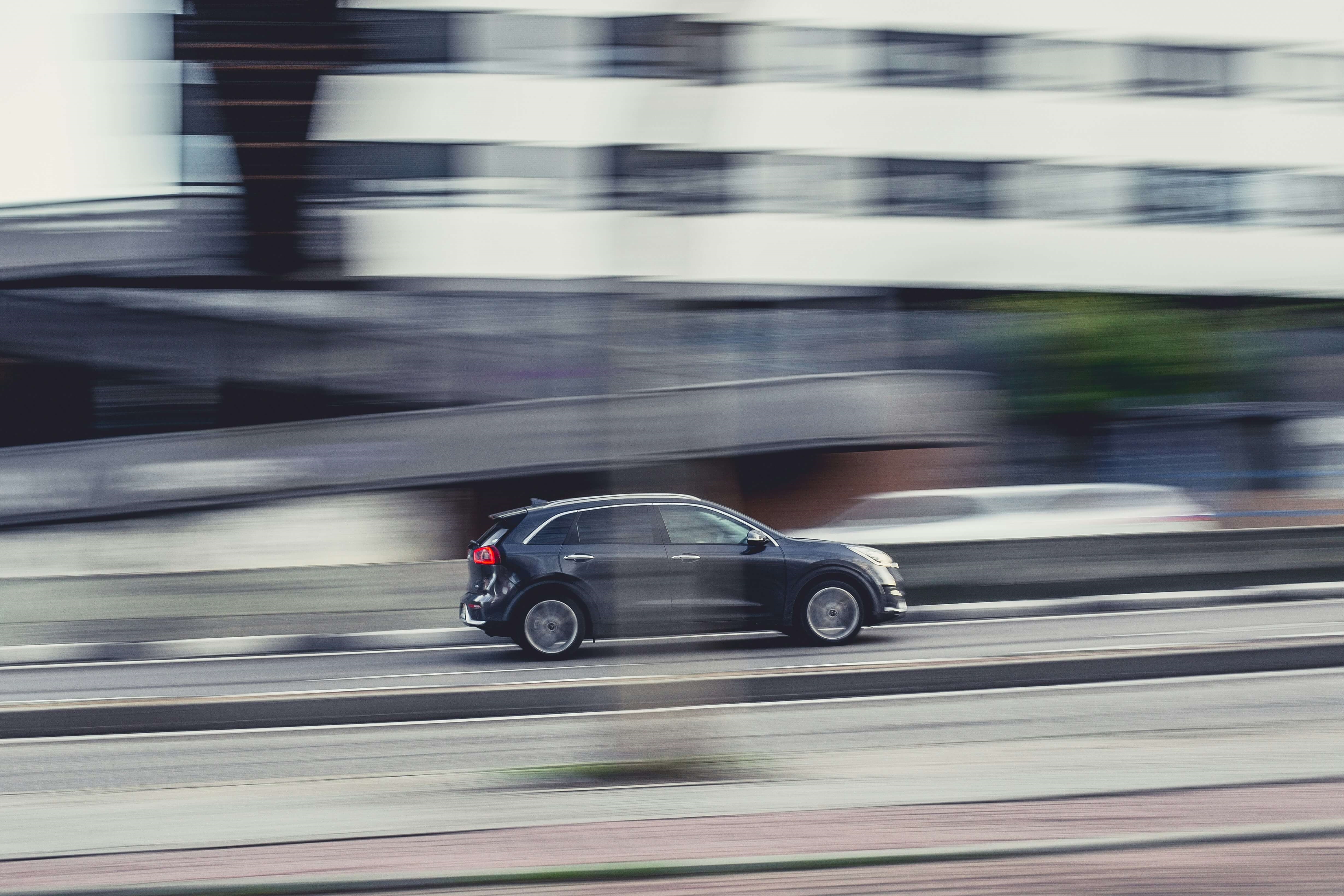 A Kia Niro driving along a highway.