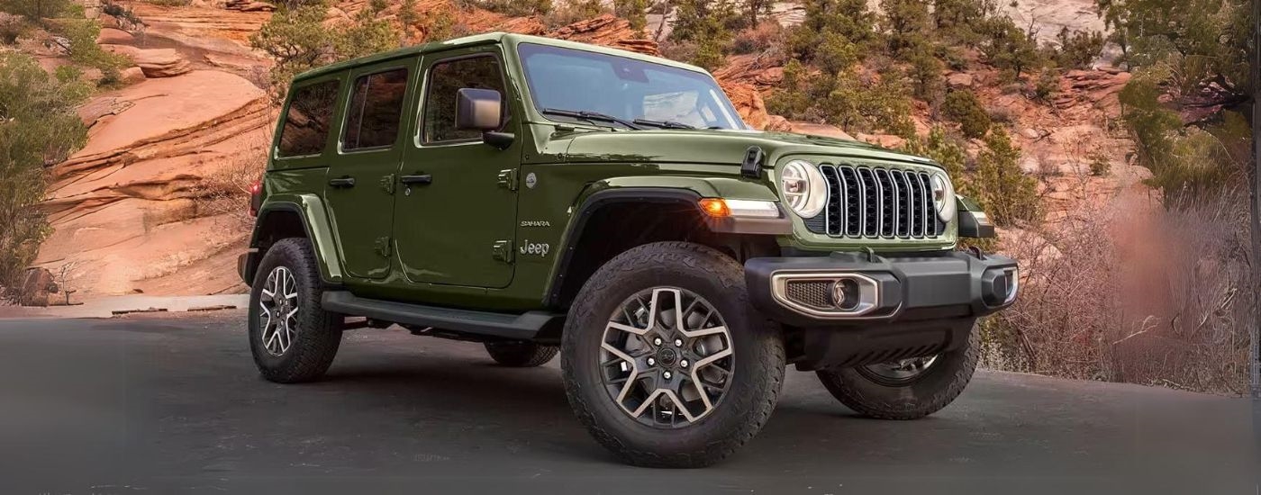 A green 2024 Jeep Wrangler Sahara Unlimited parked and angled right.