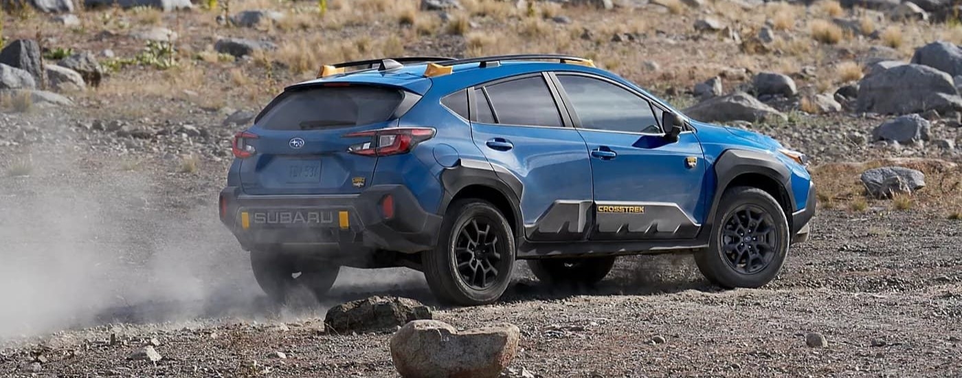 Rear view of a blue 2024 Subaru Crosstrek Wilderness driving off-road.