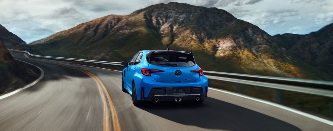 Rear view of a blue 2024 Toyota GR Corolla Circuit Edition driving around a bend.