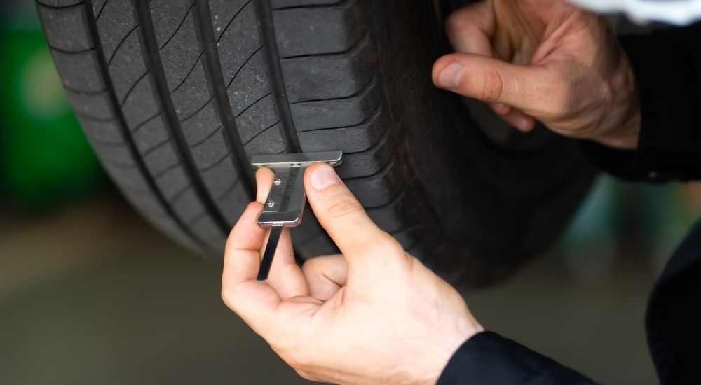 Close-up of a mechanic checking a tire's tread depth during Honda Service.