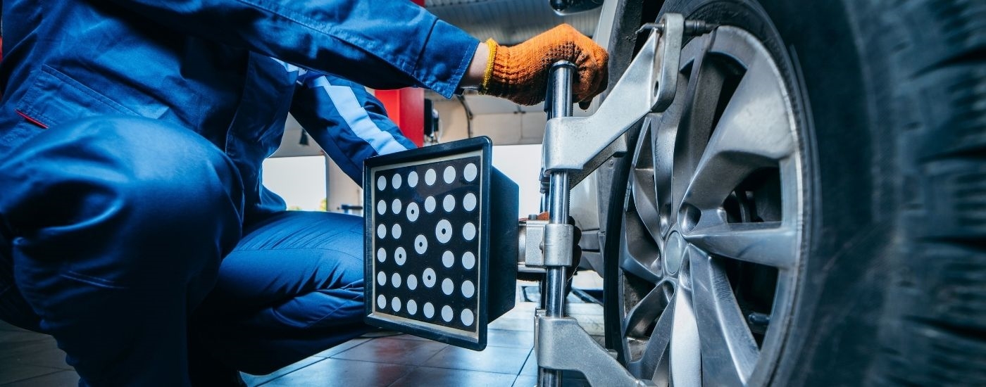 A mechanic performing a wheel alignment at a Honda service center.