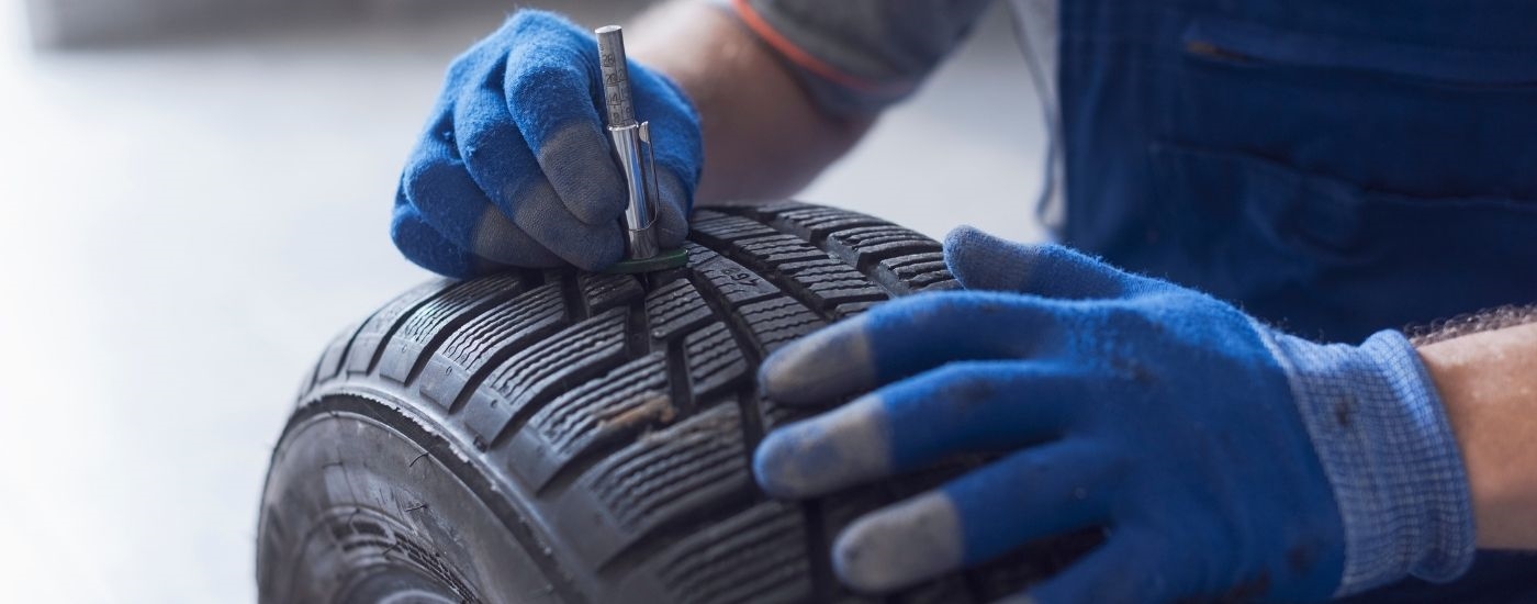 Close-up of a mechanic measuring tire tread depth.