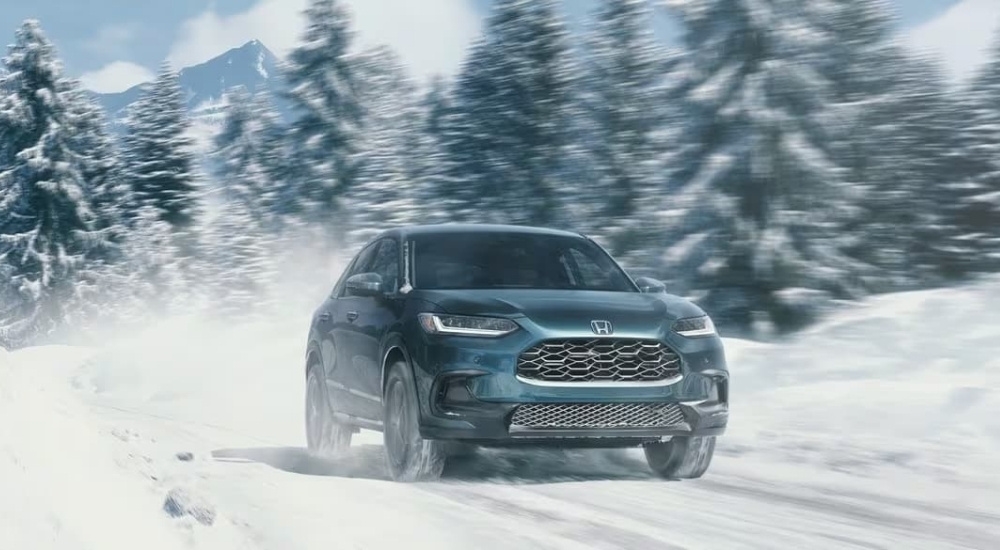 A blue 2025 Honda HR-V EX-L is shown driving on a snowy trail.