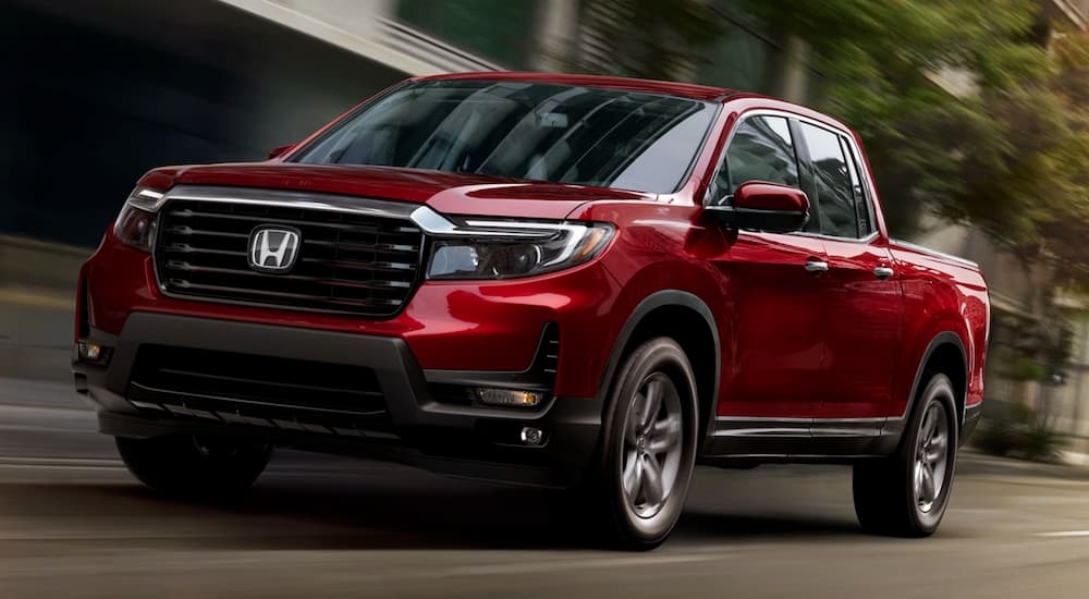 A red 2025 Honda Ridgeline RTL-E driving through a city.