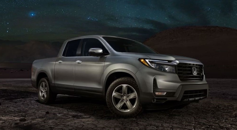 A grey 2025 Honda Ridgeline RTL-E parked on rocky terrain and angled right.