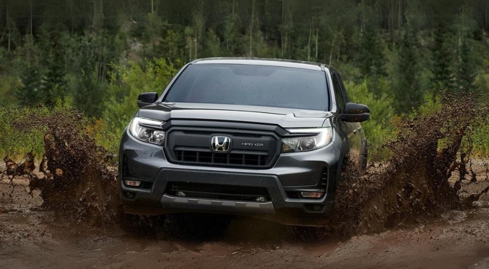 A grey 2025 Honda Ridgeline HPD+ driving over a mud puddle.