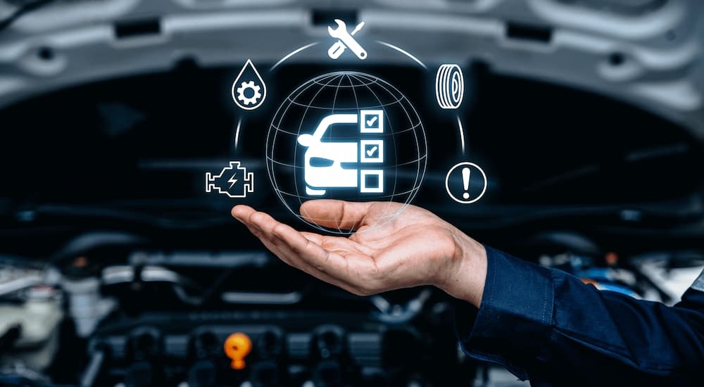 A mechanic is holding their hand out as blue simulated car repair icons float above.