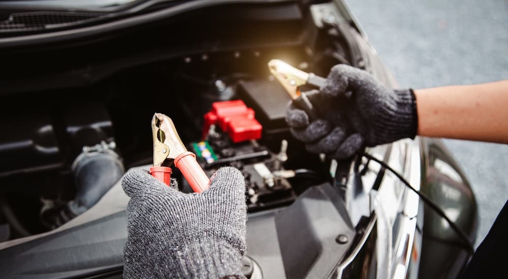 A mechanic is jump starting a vehicle's battery.