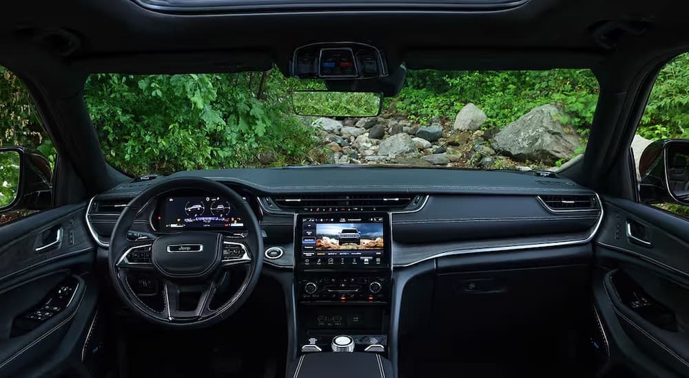 The black dashboard, steering wheel, and infotainment screen in a 2025 Jeep Grand Cherokee L.