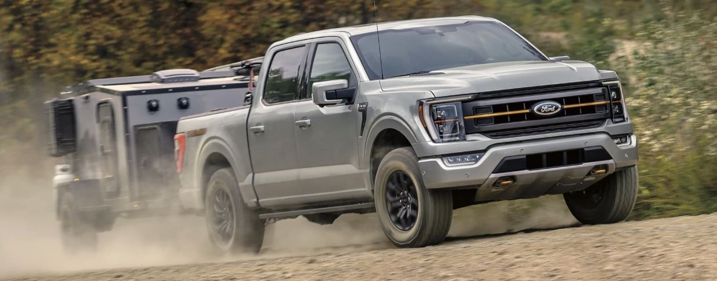 A grey 2024 Ford F-150 Tremor towing a trailer on a dirt road.