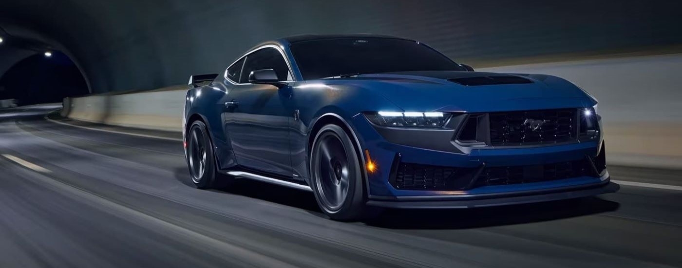 A blue 2024 Ford Mustang Dark Horse driving through a tunnel.