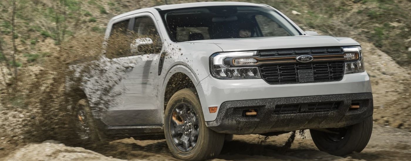 A white 2024 Ford Maverick Tremor driving over a mud puddle.