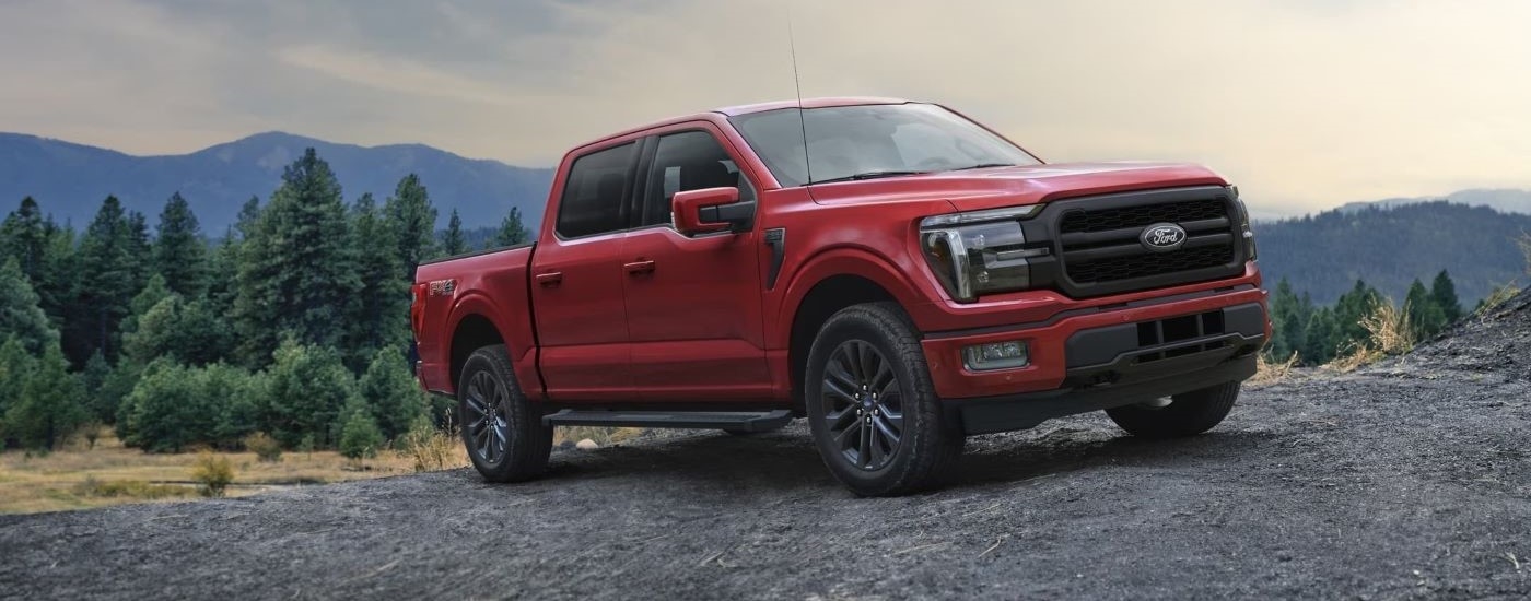 Right-angled view of a red 2024 Ford F-150 Lariat parked off-road after visiting a Ford dealer near Greenfield.