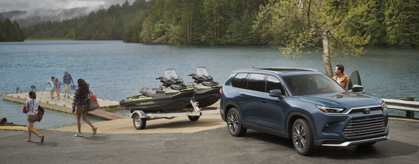 A grey 2025 Toyota Grand Highlander Platinum Hybrid MAX unloading jet skis at a lake.