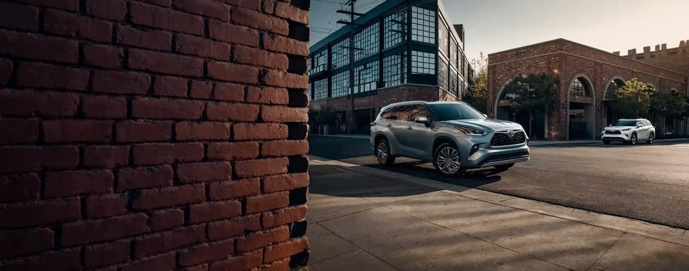 A silver 2022 Toyota Highlander driving around a city corner.