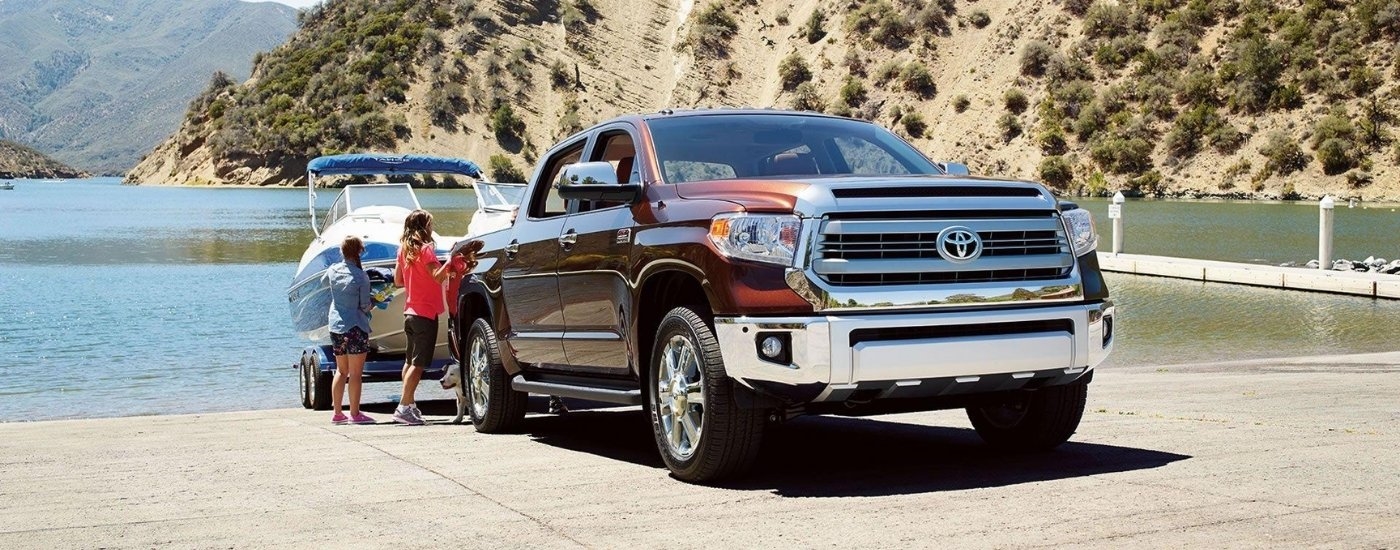 A brown 2016 Toyota Tundra for sale near Scottsville is shown towing a boat at a lake.