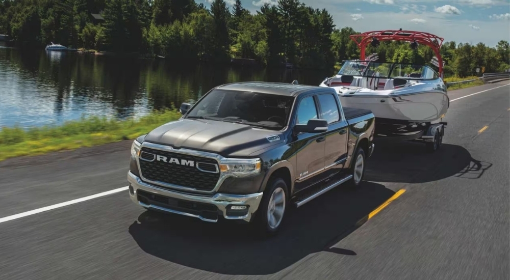 A silver 2025 Ram 1500 Big Horn towing a boat.