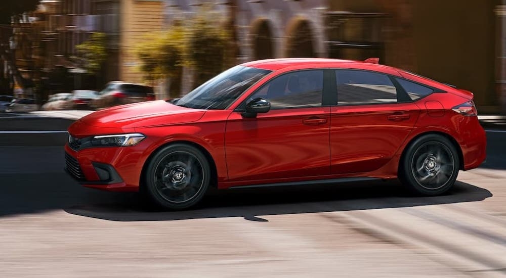 A red 2022 Honda Civic Hatchback driving through a city.